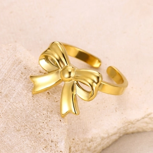 Macro shot of gold bow ring with mirror finish on natural beige stone texture