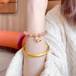 Detail of beaded sunstone bracelet with pink beads and a colorful rocking horse charm