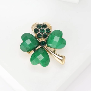 Elegant gold clover brooch with sparkling green rhinestones on white display stand