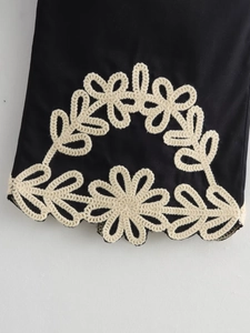 Vue détaillée du tissu en coton noir avec broderie florale délicate au crochet blanc