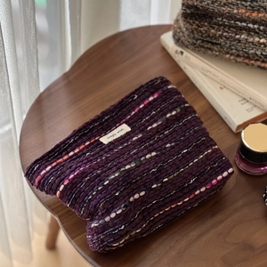 Vintage wool tweed cosmetic bag in purple knit with colorful speckled pattern on wooden desk