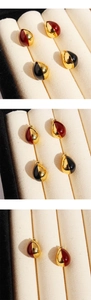 Detail of tear-drop enamel stud earrings in red-gold and black-gold on velvet