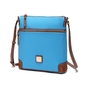 Detail of blue pebbled leather crossbody bag with brown trim and brass hardware accents