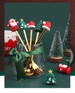 Close-up of golden Christmas spoons with Santa and tree silicone toppers in a glass cup