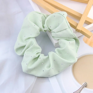 Detail of light green stretch fabric scrunchie featuring multiple small inlaid rhinestones