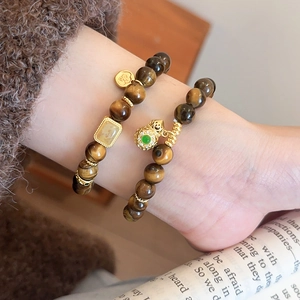 Close-up of double-layer tiger eye stone beaded bracelets with golden hollow pendants
