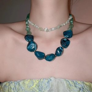 Detail of layered acrylic necklace with blue-green marble beads and small green stones