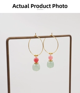 Detail of gold hoop earrings featuring pink and pale green gemstone beads in a retro style