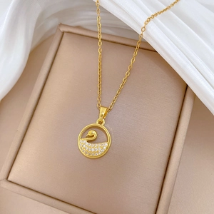 Close-up of gold hollow swan pendant with sparkling crystals on white silk