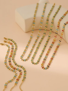 Detailed view of gold leaf necklaces with multi-color enamel charms on display