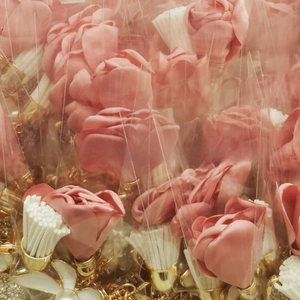 Close-up of pink fabric floral pendants with gold metal base in protective packaging