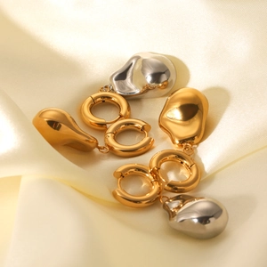Detailed macro of gold and silver hoop earrings with irregular baroque liquid metal pendants