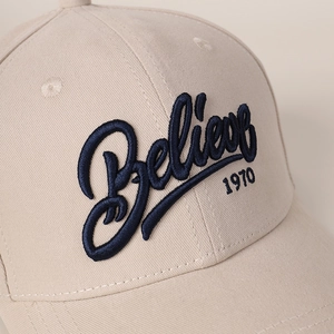 Close-up of beige twill cotton baseball cap with blue 3D embroidery showing 1970 detail