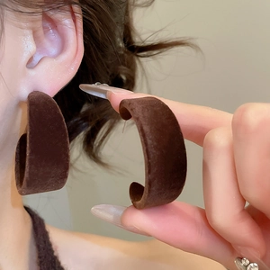 Détail de boucles d'oreilles en C marron avec texture velours doux sur l'oreille
