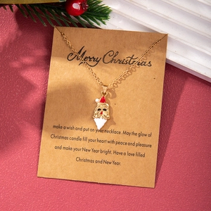 Close-up of golden Santa Claus enamel pendant on a kraft paper Christmas wish card