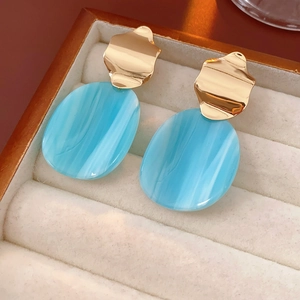 Vue macro de boucles d'oreilles dorées avec pendentifs en résine marbrée bleue
