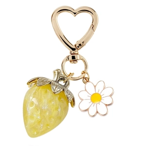 Detail of yellow resin strawberry keychain with golden heart hook and small white flower