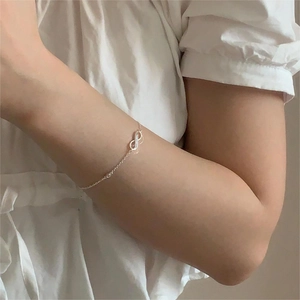 Minimalist S925 sterling silver infinity bracelet worn on wrist in natural light