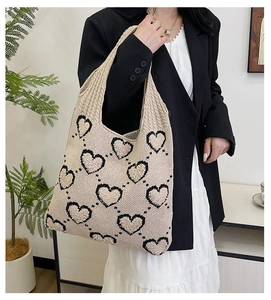 Sac fourre-tout en tricot beige à cœurs, porté par un mannequin en veste noire et robe