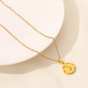 Macro shot of 18K gold plated stainless steel moon pendant necklace detail on porcelain