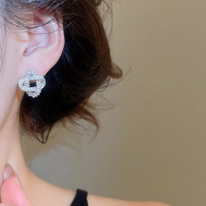 Close-up of geometric intertwined silver earrings with white zircon on model's ear