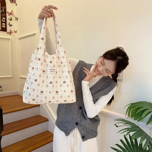 Detailed close-up of quilted tote bag with brown bear patterns and woven brand label