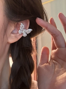 Close-up detail of silver butterfly ear cuff with sparkling cubic zirconia on model ear