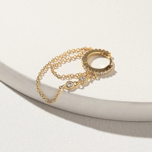 Detailed macro view of 18K gold-plated huggie earrings with zirconia chain tassels