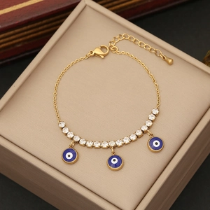 Golden evil eye bracelet with blue charms and white cubic zirconia on a jewelry box