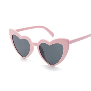 Detailed side view of pink heart-shaped sunglasses with dark grey lenses and glossy finish