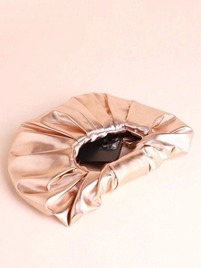 Detail of rose gold cloud clutch bag showing metallic pleated texture and interior capacity