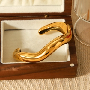 Detailed macro view of an irregular wave pattern gold plated stainless steel cuff bracelet