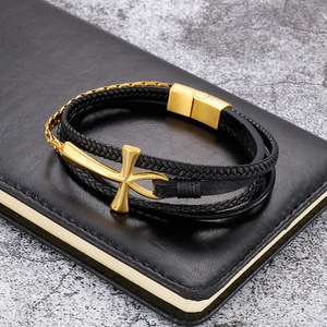 Detailed close-up of a multilayer black leather bracelet with golden cross and magnetic clasp
