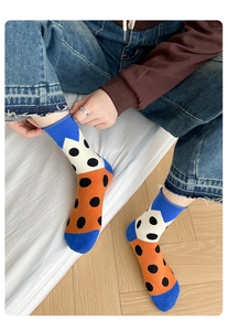 Detail of vibrant blue and orange knitted socks with black polka dots and ribbed cuffs