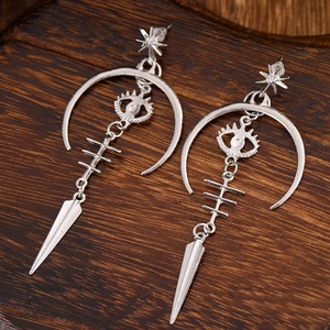 Gothic silver dangle earrings with star, crescent moon, and evil eye charms on wood