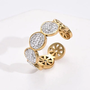 Detailed close-up of a gold hollow-out ring with sparkling white cubic zirconia stones