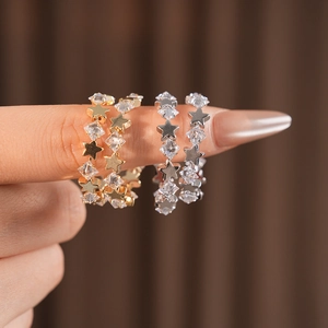 Close-up of stacked gold and silver star rings set with sparkling clear gemstones