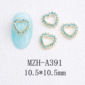 Détail d'un bijou d'ongle cœur doré 10,5mm avec strass bleu clair sur ongle bleu