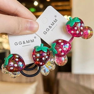 Detail of red strawberry hair ties with white dots and green leaves on black elastic cord