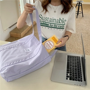 Close-up of a lilac canvas tote bag with a small white label on a white T-shirt