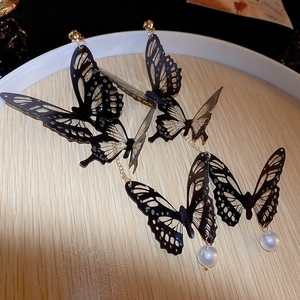 Détail de longues boucles d'oreilles papillon noir ajouré avec perle d'imitation blanche