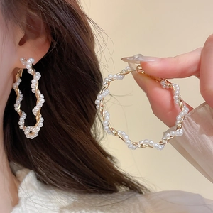 Detail of twisted gold hoop earrings with small white pearls and vintage French design