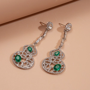 Détail de boucles d'oreilles gourde en argent avec pierres vertes et micro-diamants