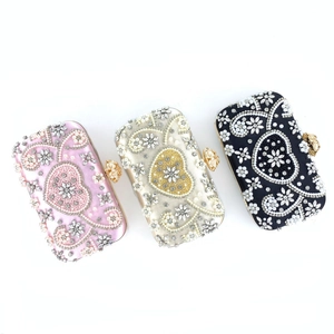 Detailed view of pink, champagne and black evening bags with pearl heart embroidery