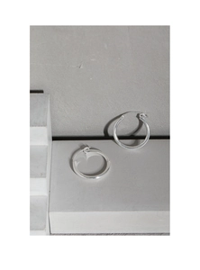 Close-up of minimalist S925 sterling silver hoop earrings on a grey textured background