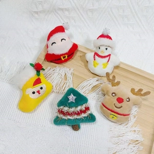 Detailed view of plush Christmas ornaments with intricate embroidery on wood tray