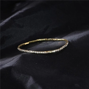 Macro shot of 2.0mm gold single-row rhinestone stretch bracelet on dark velvet