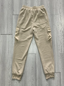 Detail of khaki quilted cargo pants showing elastic waistband and textured grid pattern