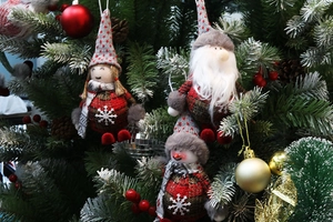 Détail de poupées de Noël en peluche avec motifs à carreaux rouges sur un sapin