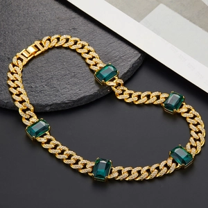 Dettaglio catena cubana dorata con pietre verde smeraldo e strass scintillanti